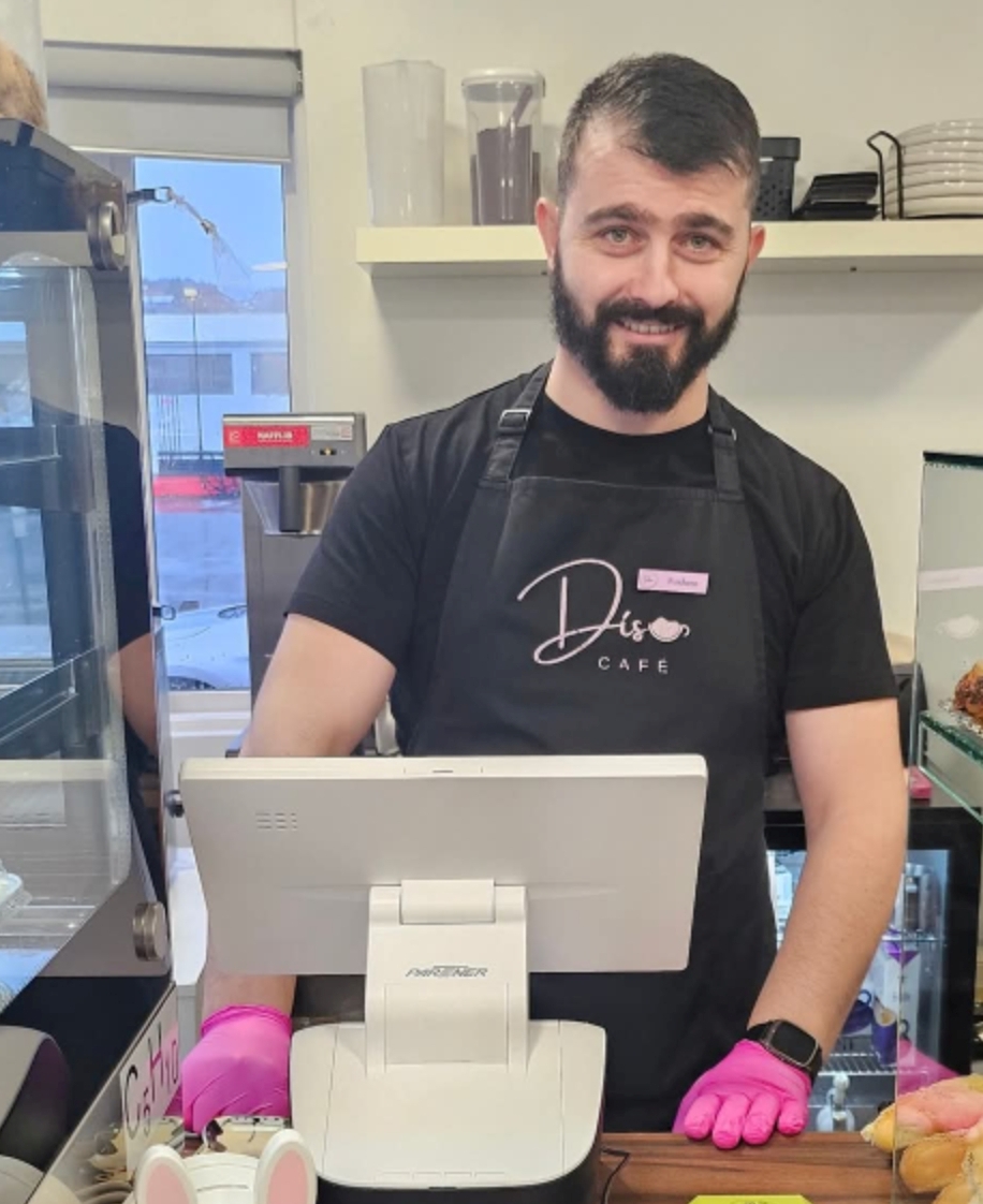 Roxhens Qypi við kassann, hann býður reglulega upp á albanskt bakkelsi við miklar vinsældir.