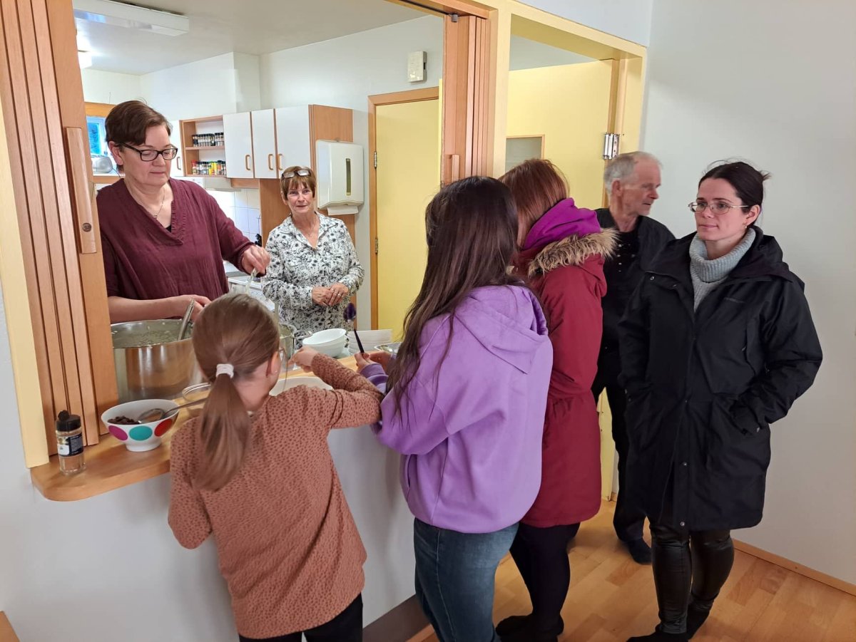 Linda Ásgeirsdóttir formaður Ferðamálafélags Hríseyjar skammtar graut á diska, að baki hennar stendu…